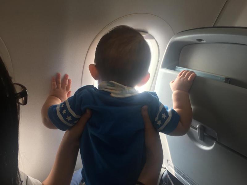飛行機の窓から外を見る子供